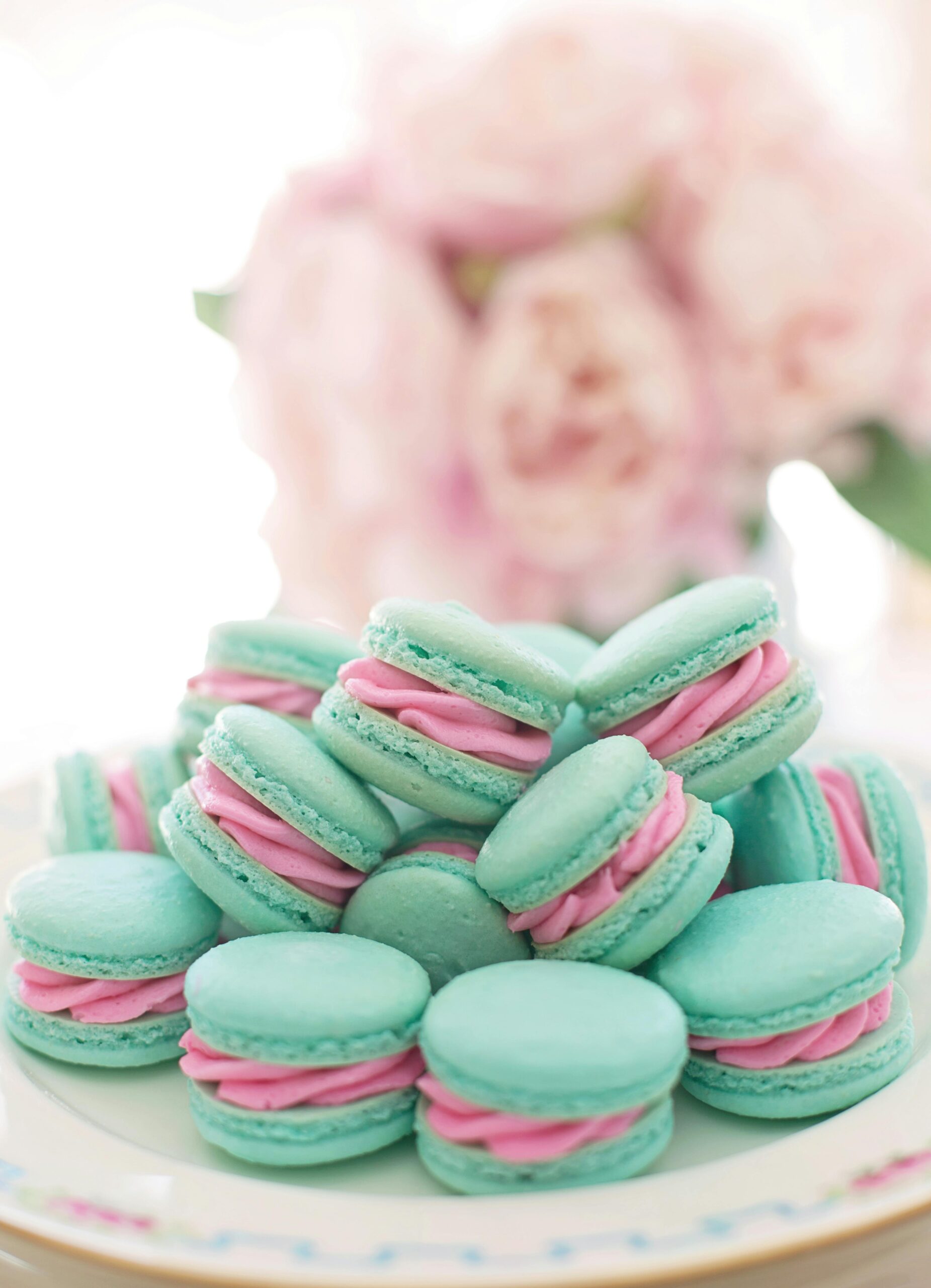 A stack of blue macarons with pink filling on a decorative plate, perfect for food photography.